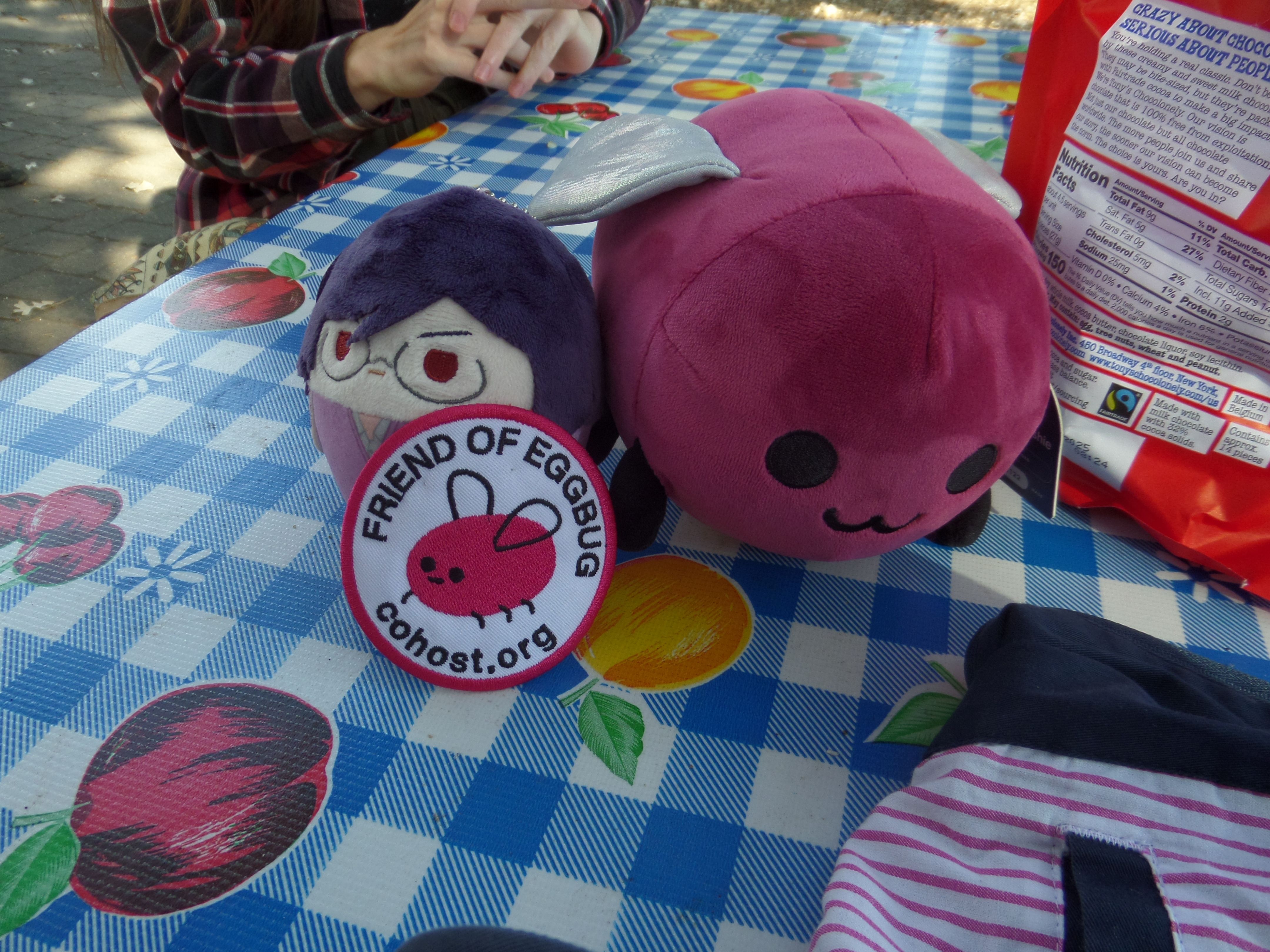 It’s Eggbug! He’s on the table with another plushie and a “Friend of Eggbug” patch.